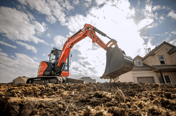 A Kubota excavator digging dirt on a construction site