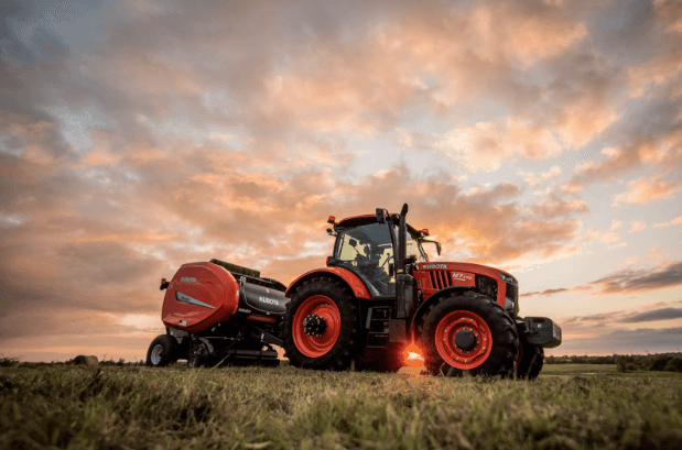 Kubota Ag Tractor pulling a baler attachment on a scenic field